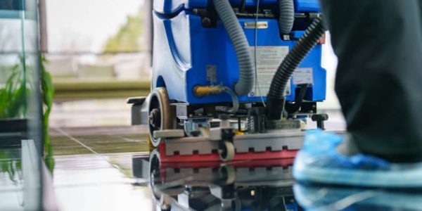 Worker cleaning office lobby floor with machine